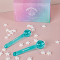 Two turquoise 'Aquamarina' ice globes with a pink and blue box in the background on a pink surface.