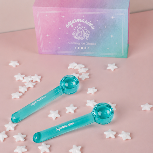 Two turquoise 'Aquamarina' ice globes with a pink and blue box in the background on a pink surface.